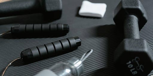 Objetos de malhação, pano branco e garrafa de água vazia no chão