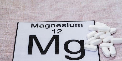 Símbolo do magnésio com comprimidos brancos ao lado.